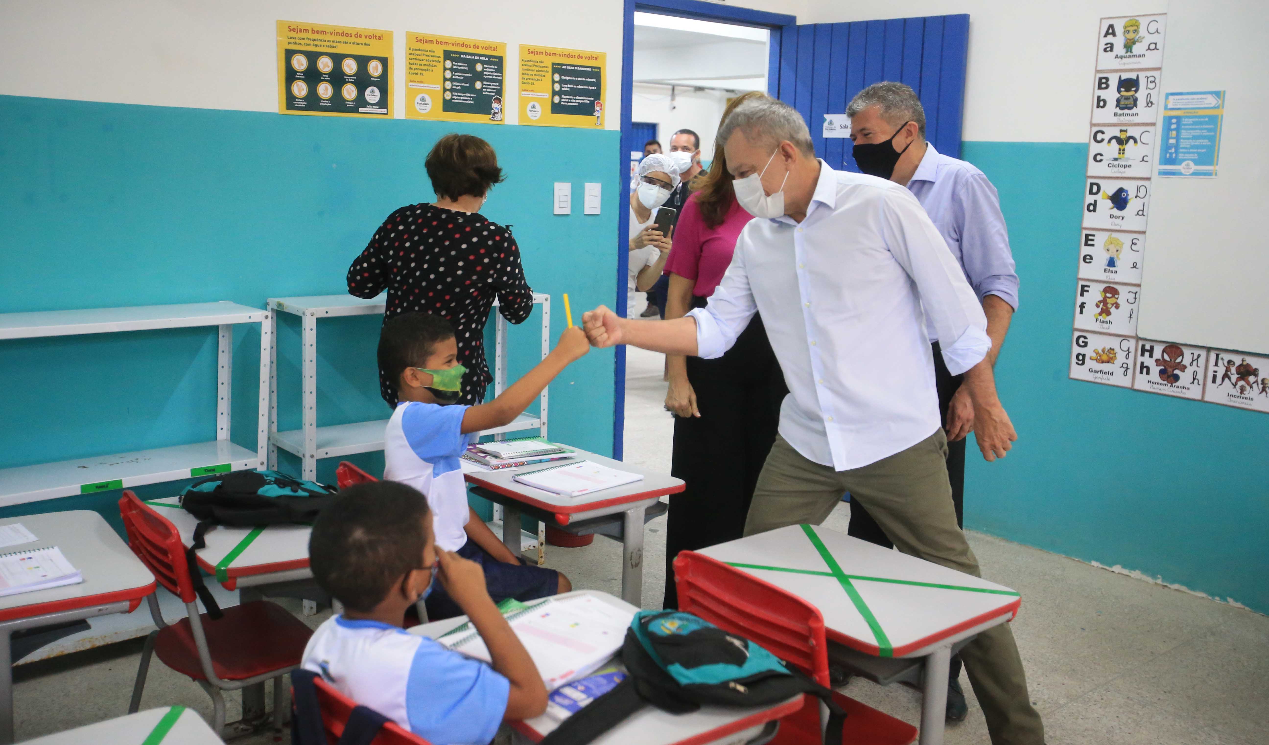 prefeito cumprimenta um aluno em sala de aula